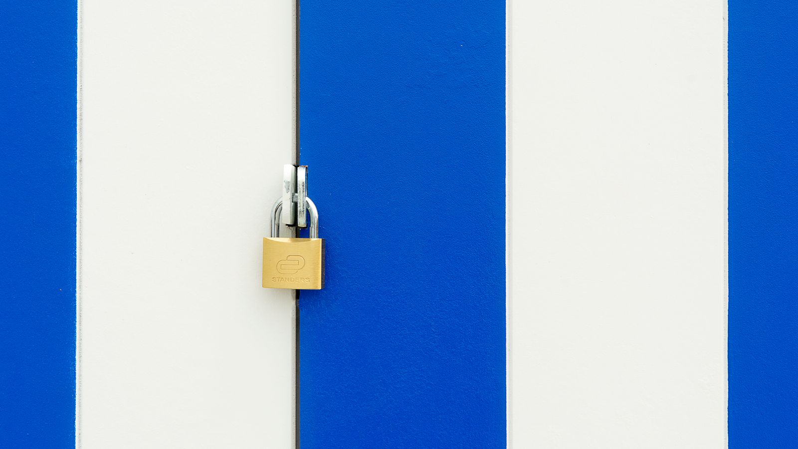 A padlock securing a blue and white striped door, symbolizing privacy and restricted access.